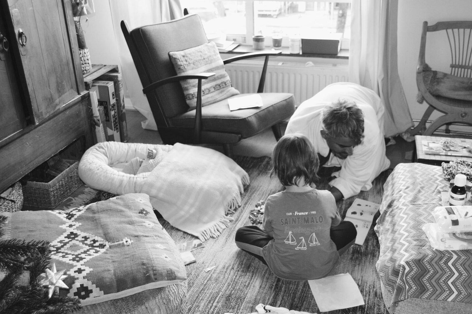 Vader speelt met oudste kind, baby slaapt